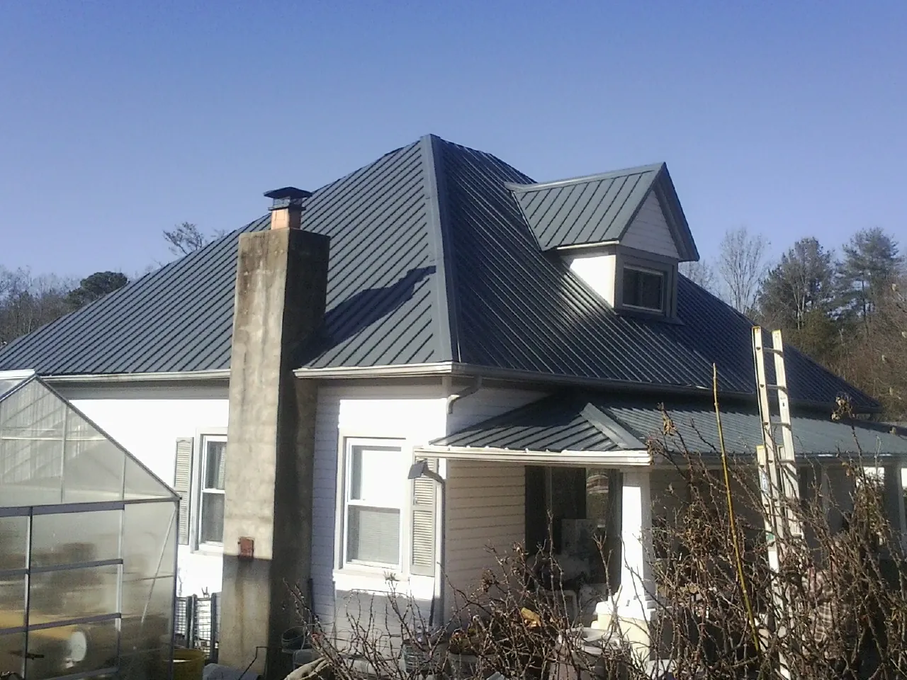 Dark blue standing seam metal roof on a white farmhouse with dormer — Slate & Tile Roof Repair by Roofing Brothers in Beach City