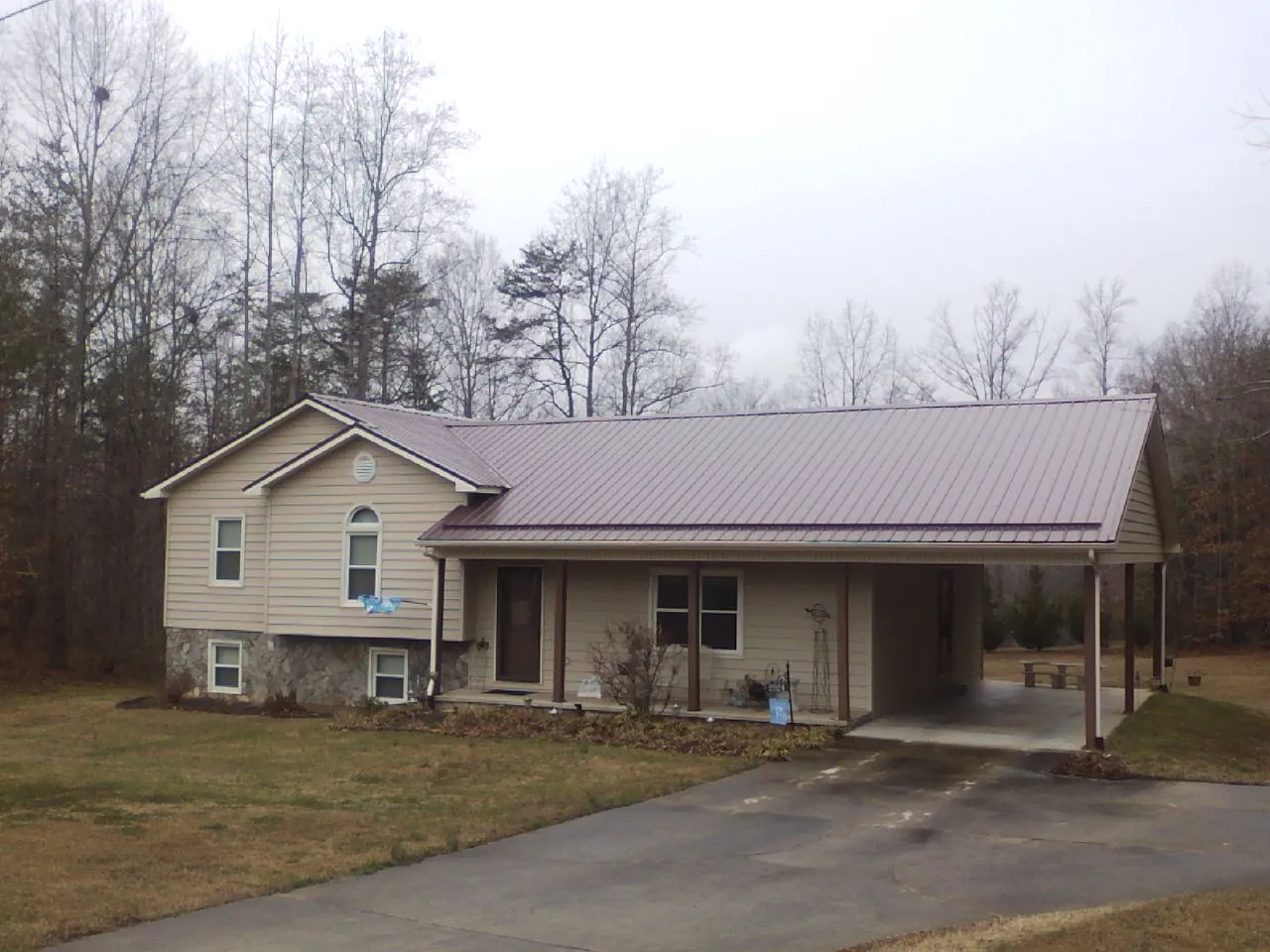 Burgundy metal roof on a tan split level home with an attached carport in Beach City