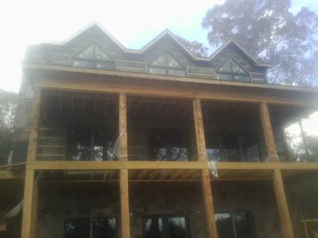 Dormers and porch framing on a large log home under construction — Roof Coating work by our crew in Beach City