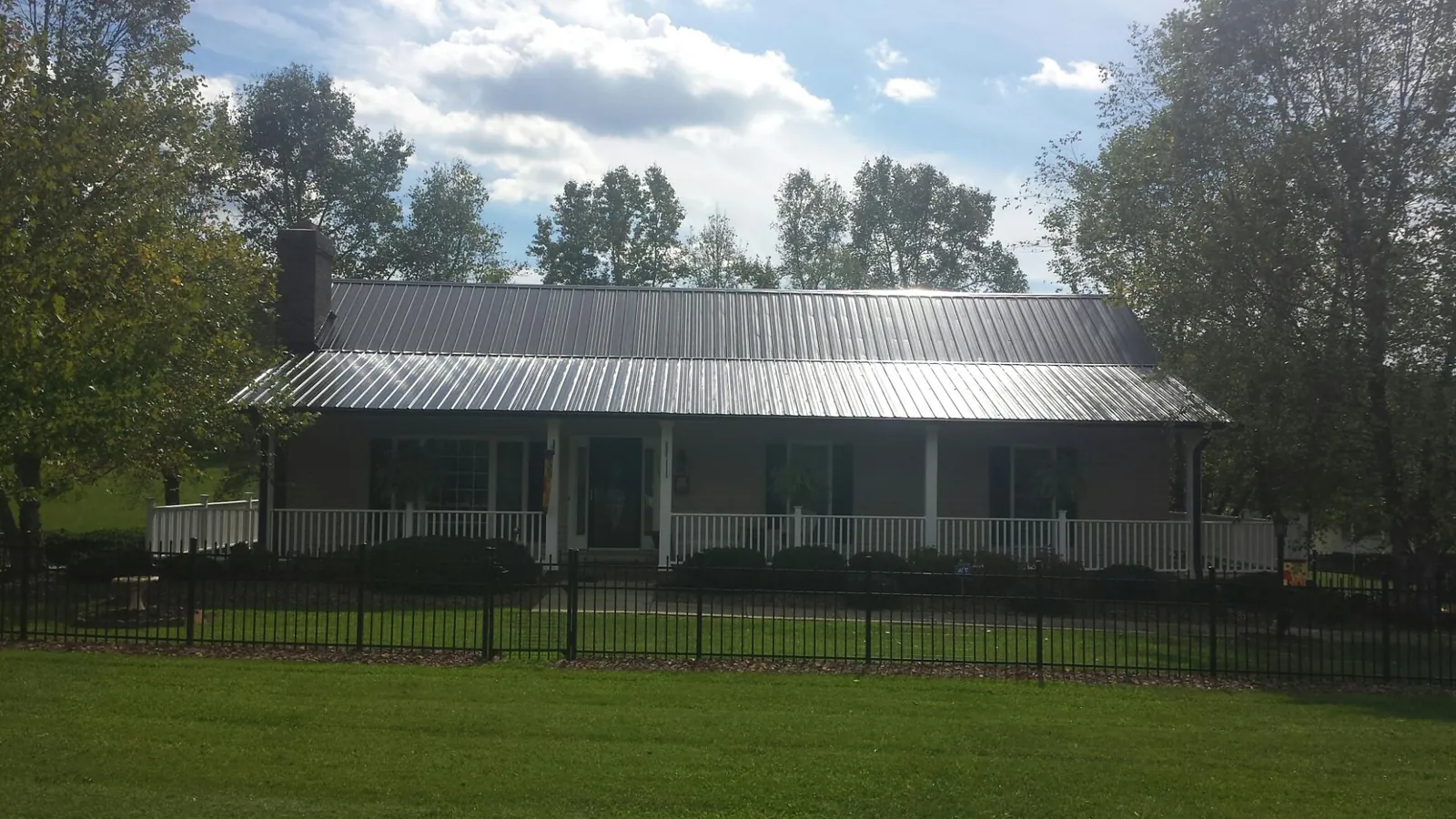 Gray metal roof on a brick ranch with a full width front porch — Gutter Guard Installation work by our crew in Beach City