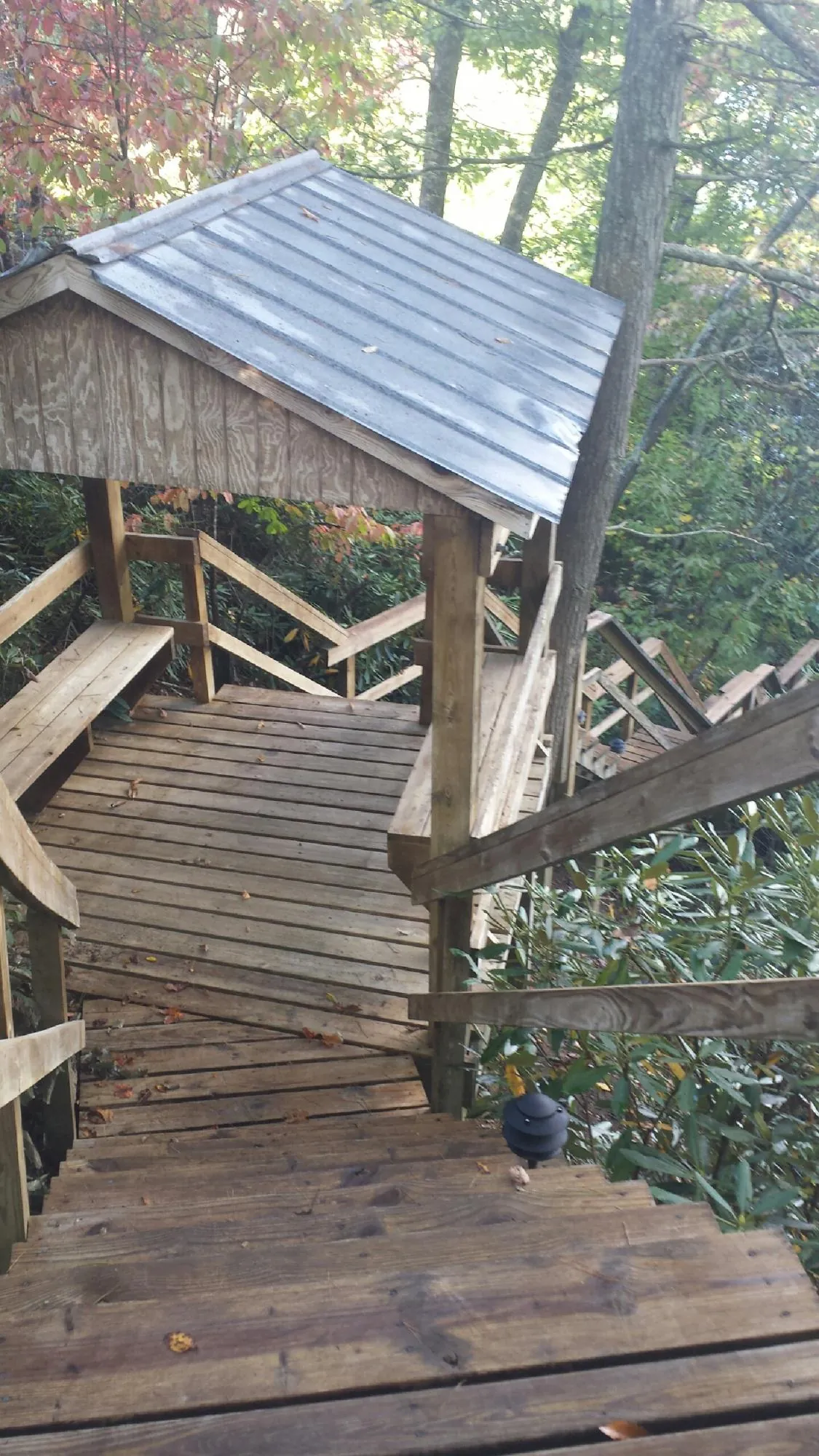 Metal roofed shelter over wooden steps on a wooded walkway — Skylight Repair & Installation work by our crew in Beach City