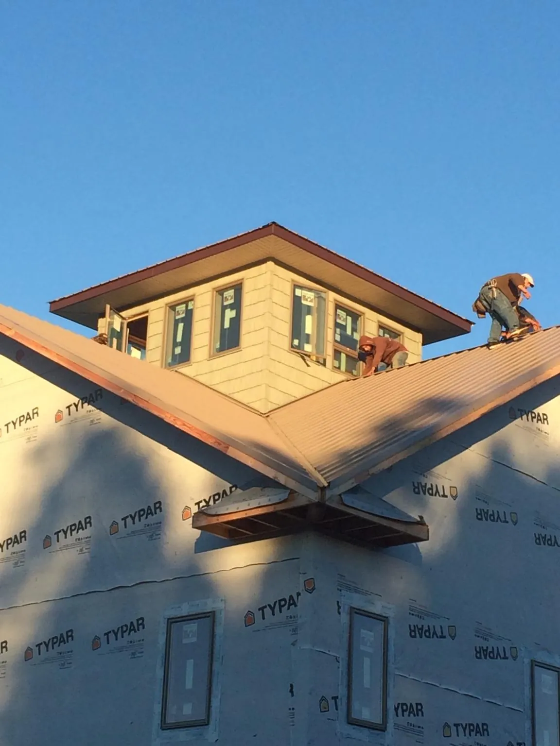 Roofers working around a rooftop cupola on a new metal roof at sunset — Roof Waterproofing in Beach City by Roofing Brothers